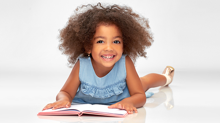 Happy young girl learning to read